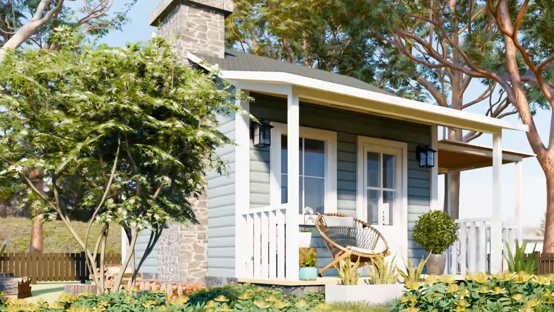 exterior of the dainty house with grey roof and blueish grey facade, front porch with a round chair next to the front door, side porch with white picket fence and a seating area, lots of plants and flowers around the house