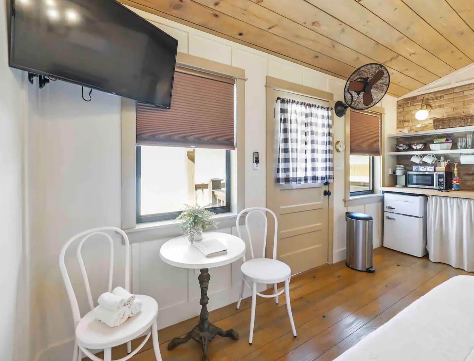 Dining area with white chairs a table and a flatscreen TV