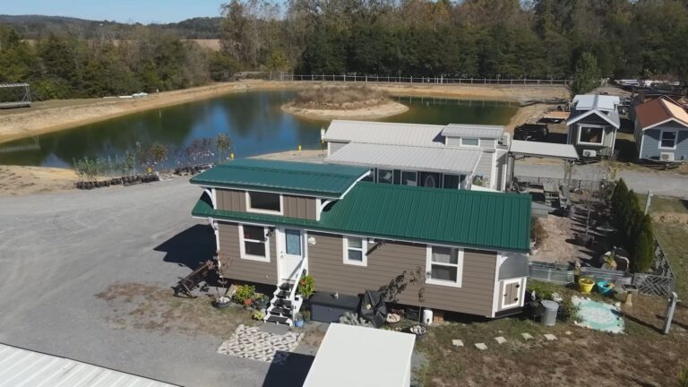 exterior of Dorothy's THOW with brown wood siding and a green metal roof, white frame around the door and windows