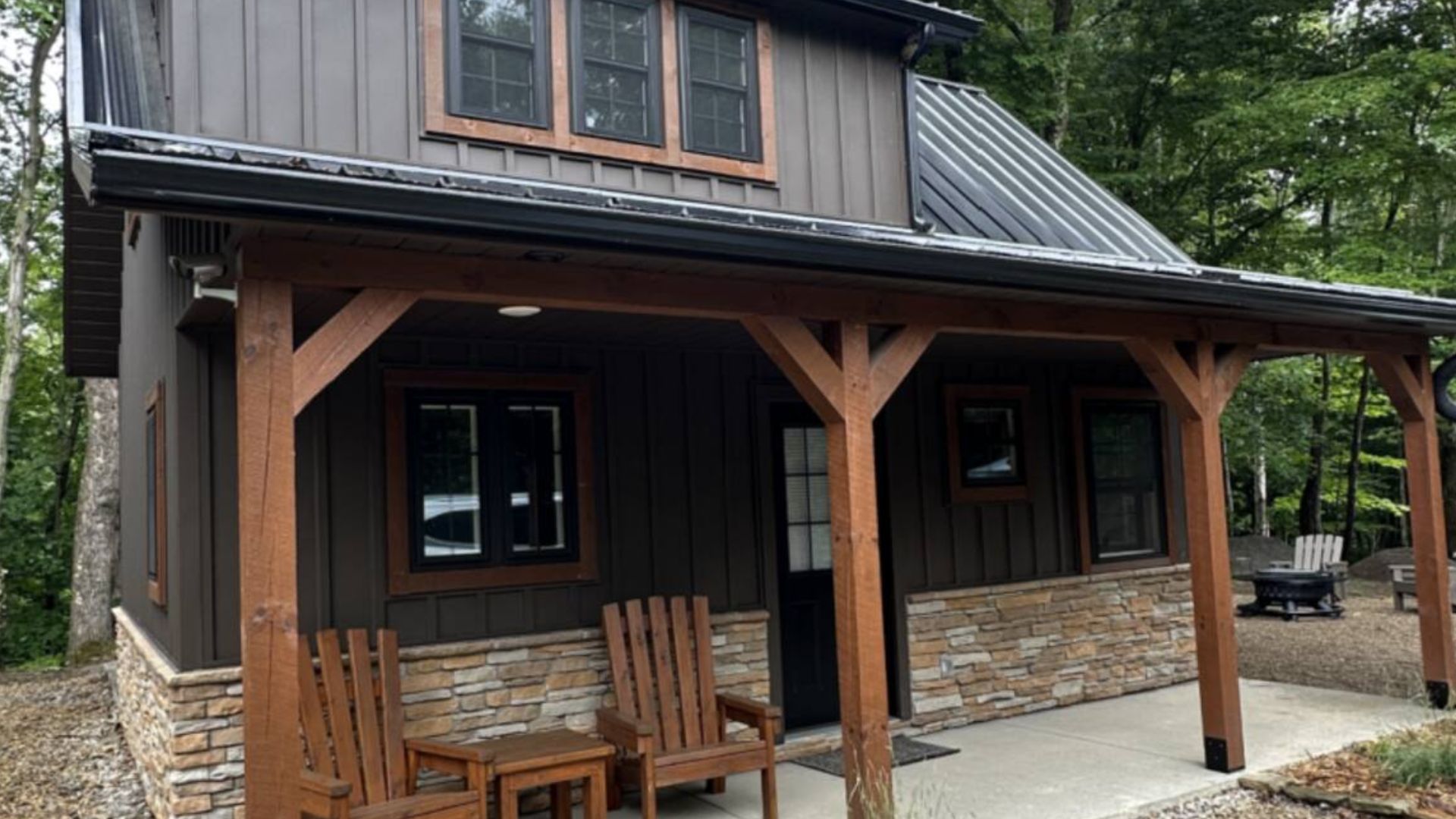 a small rustic cabin with a metal roof and a rainwater collection tank sits in a wooded area