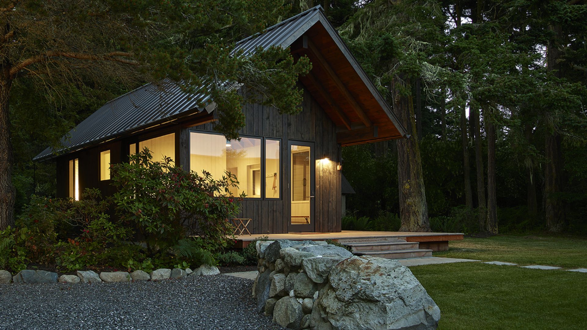 Exterior of a cabin in a forest with lights turned on