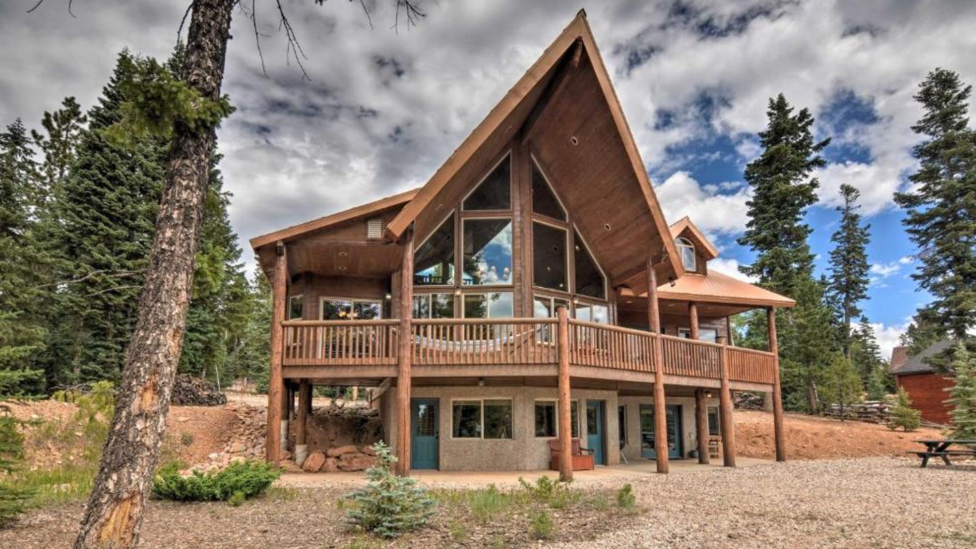 exterior of the back side of the cabin with a seating area around the fire pit, pine trees around the property