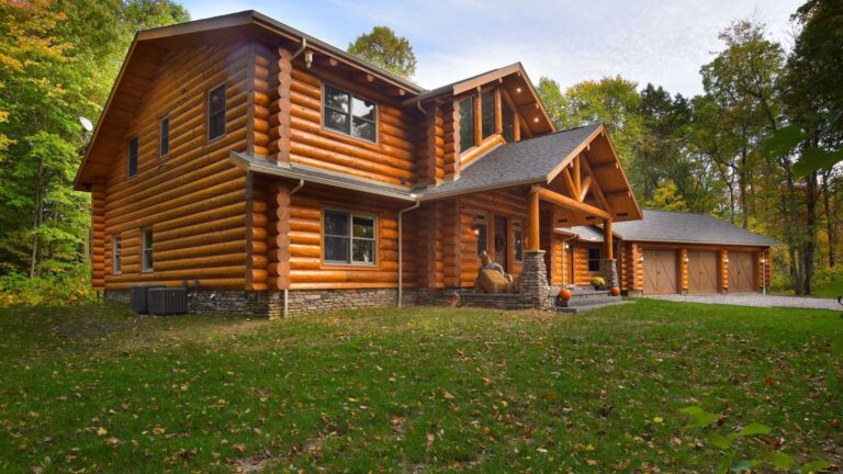 exterior of the log cabin with an adjacent three-car garage, surrounded by trees