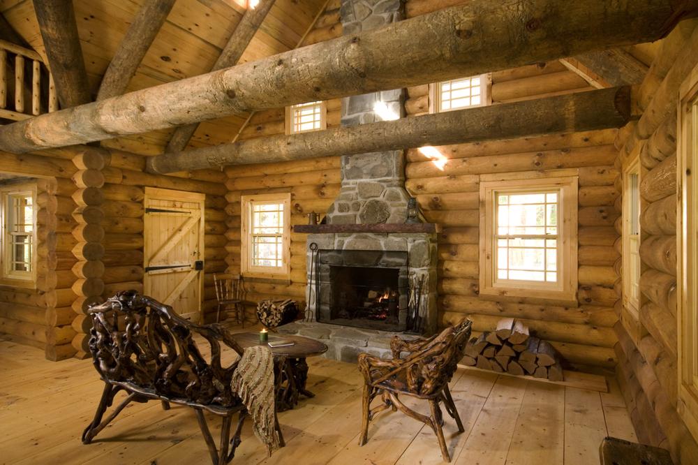 Living room of a cabin with carved chairs and stone fireplace