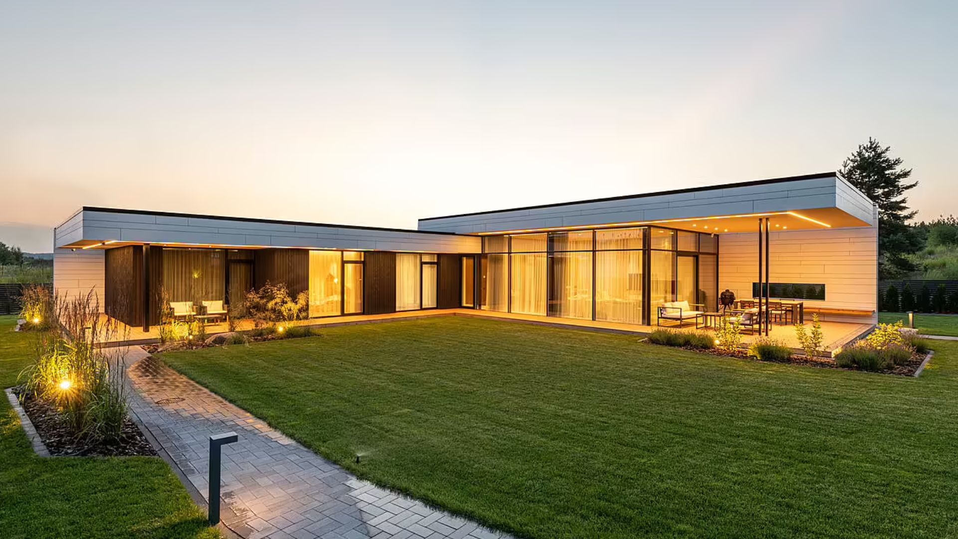 modern mansion with lights on at dusk