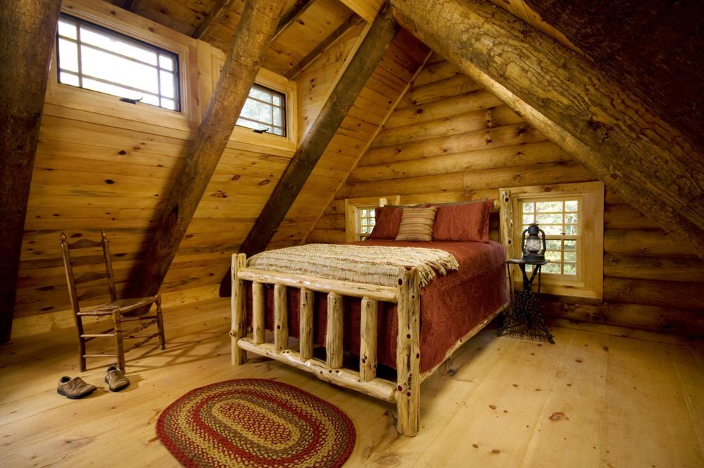 Master bedroom in a cabin with a wooden bed wit red bedding