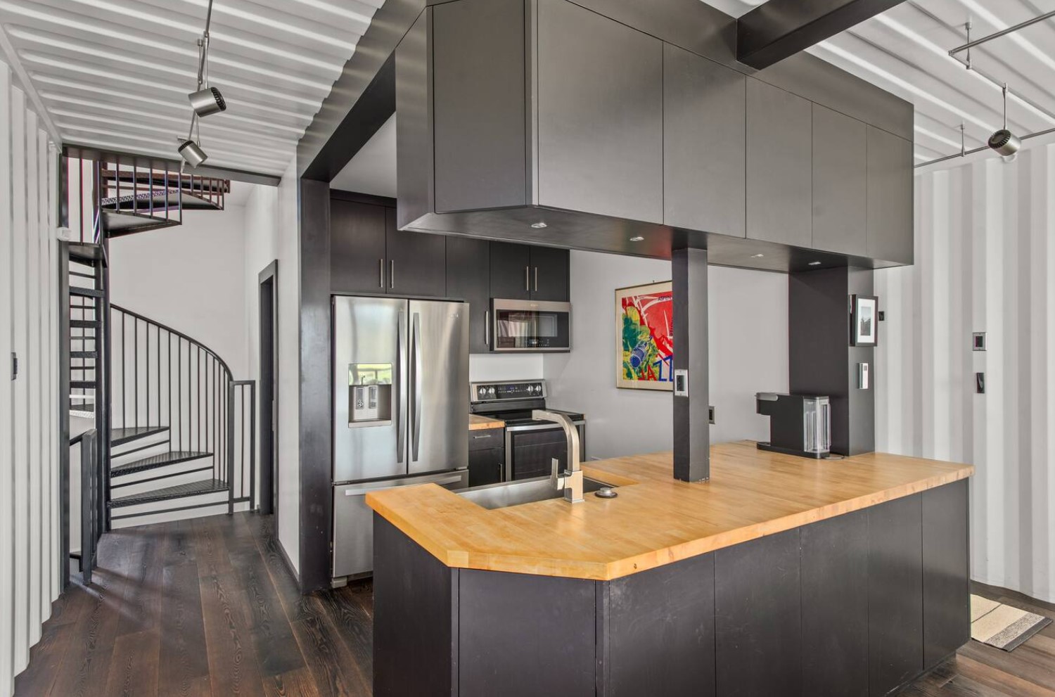 Modern black kitchen with stainless steel appliances and an artwork