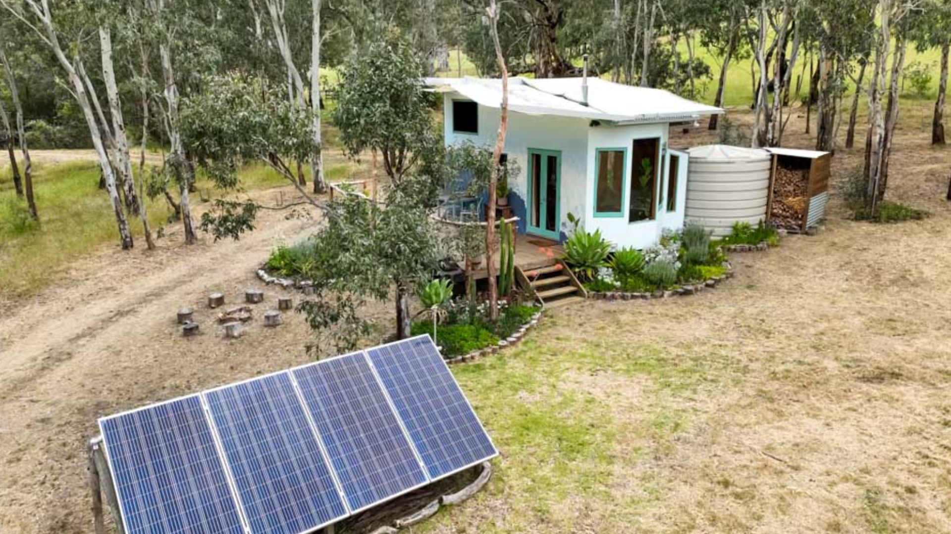 exterior of a tiny home with a lot of plants around it and an ocean painted on the wall