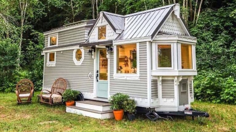 exterior of the light grey THOW with white frames around windows, lots of cool gable work