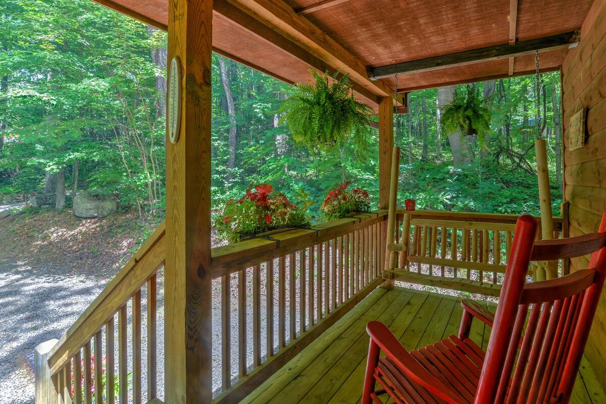 porch of a cabin with a red chair and plants