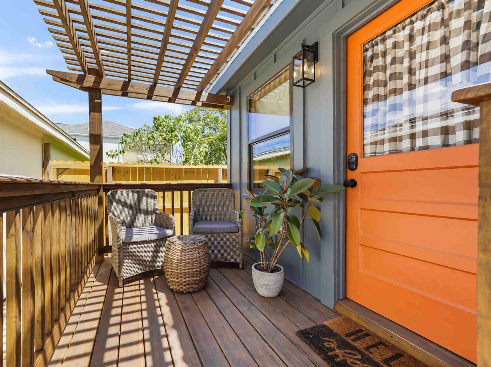 Porch of a tiny home with orange door and a lounge area