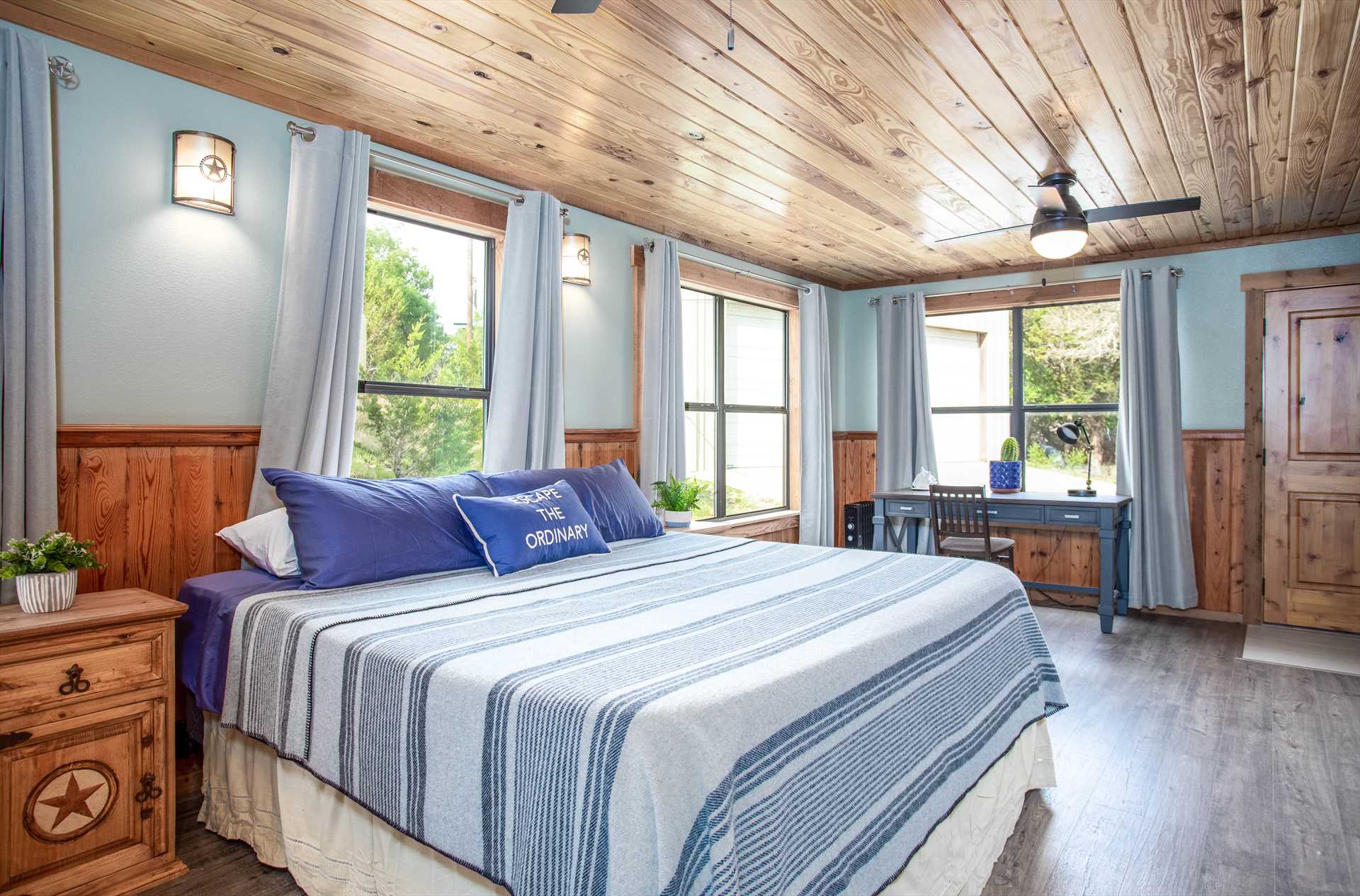 Spacious blue bedroom with a table and a king-sized bed