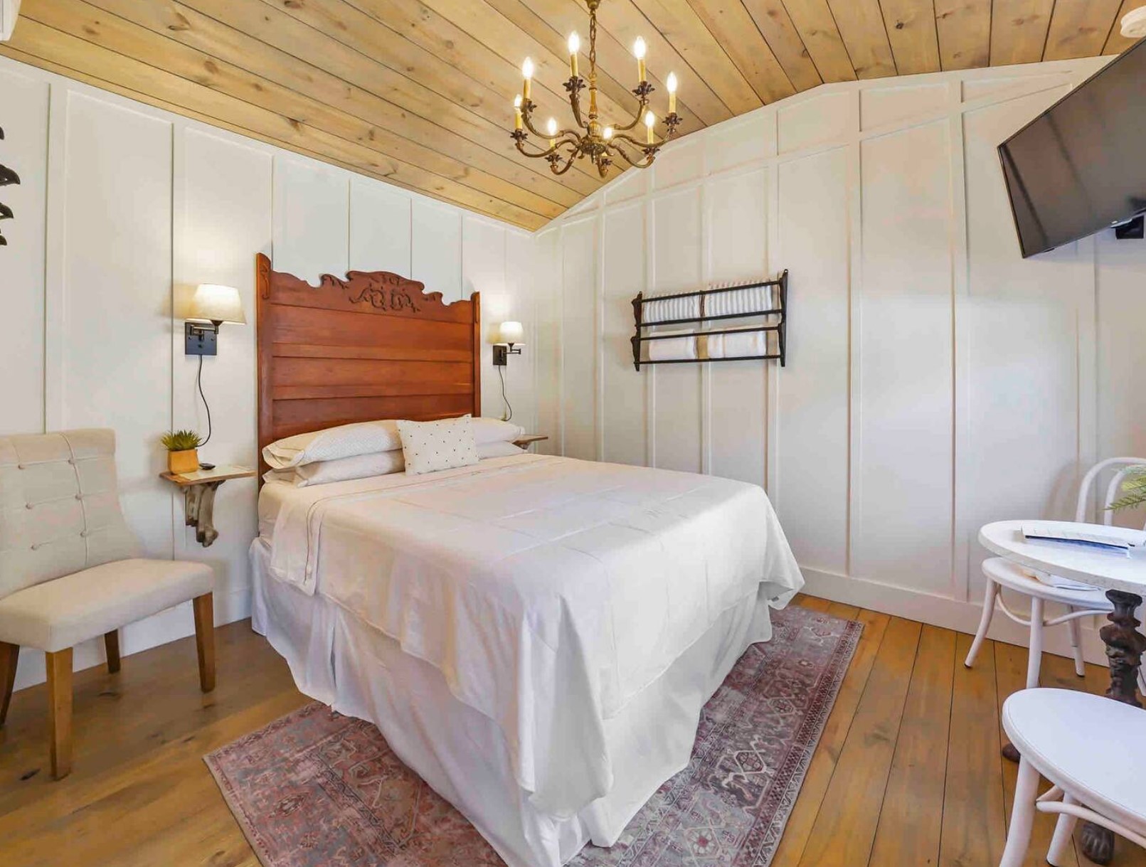 Tiny bedroom with a wooden bedframe and a chandelier