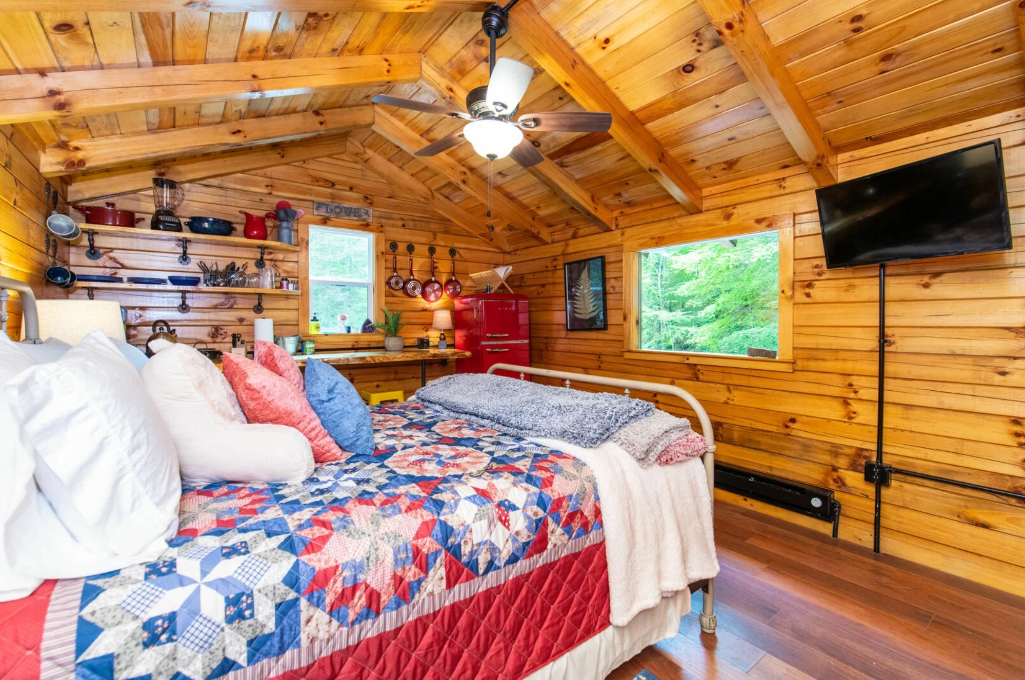 Tiny kitchen in a cabin with a red fridge and exposed shelves