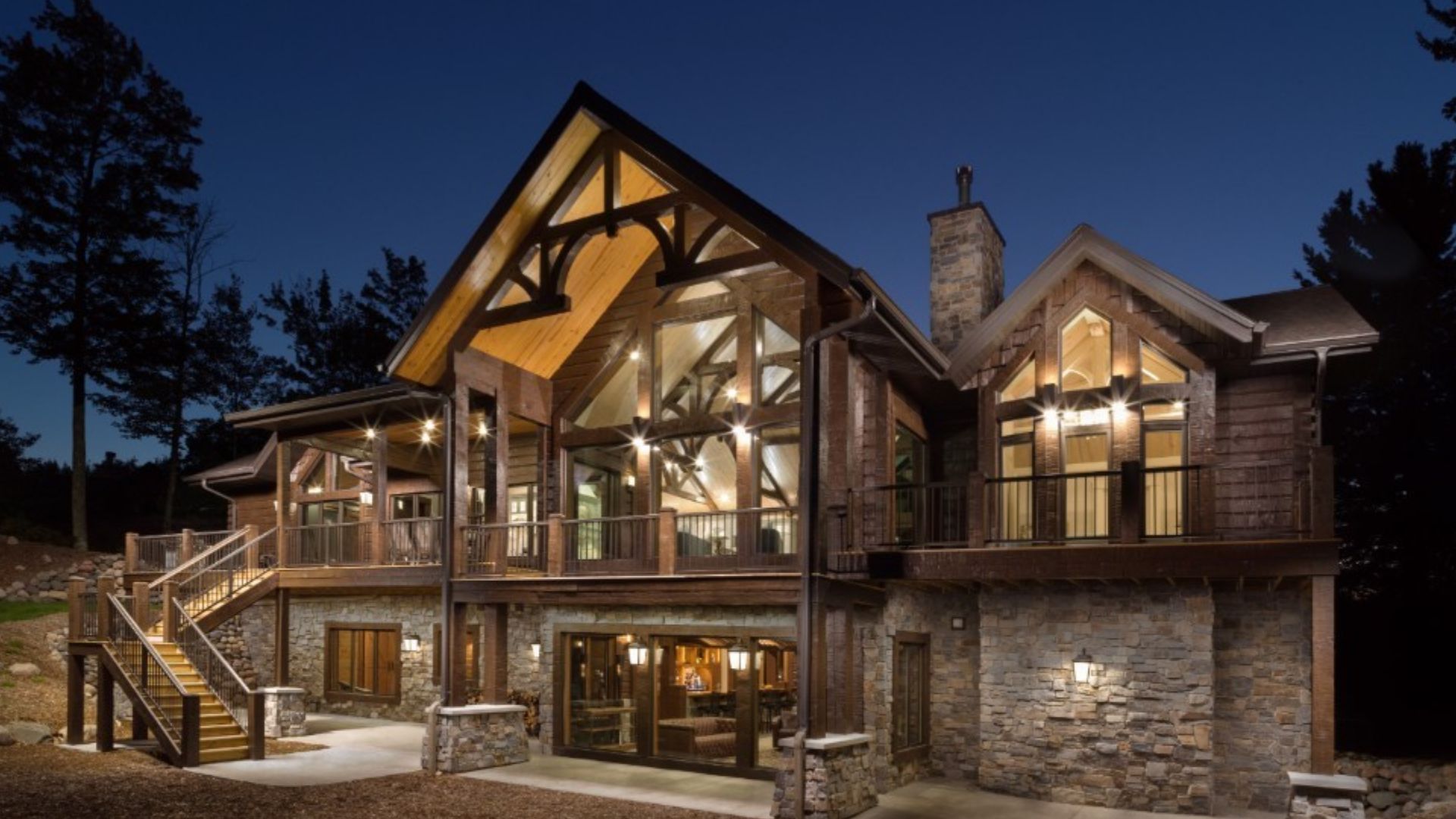 beautiful log mansion at night with lights on