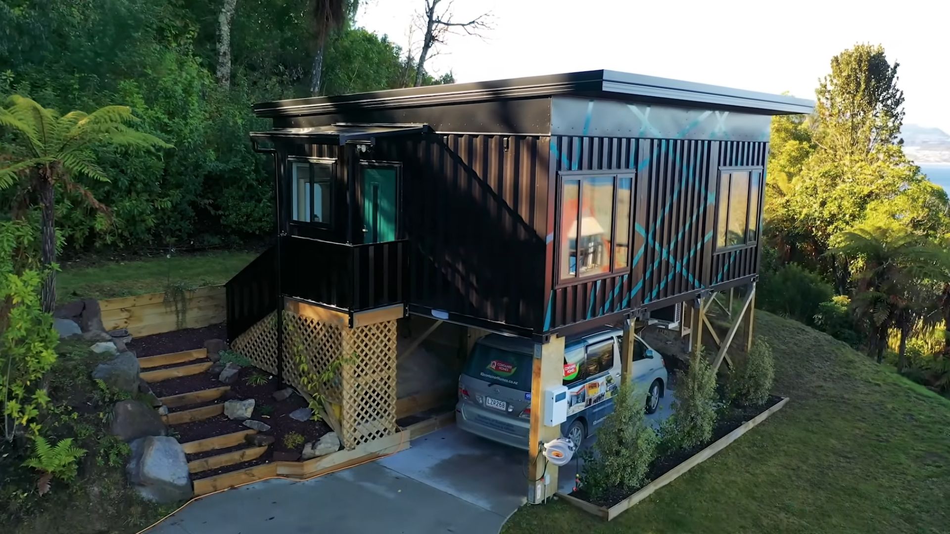 Elevated lakeside container home with a deck and carport