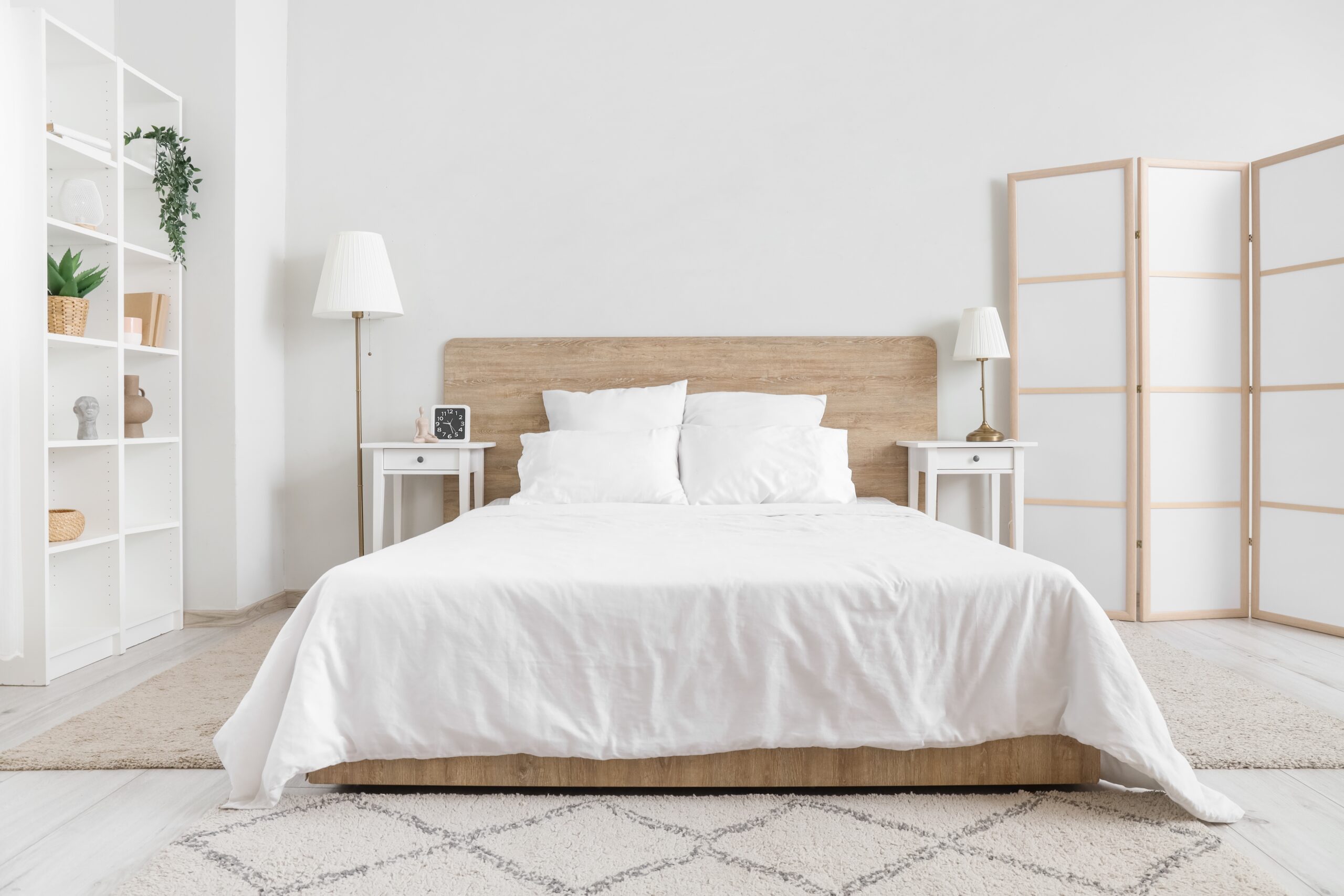 White bedding on a wooden bed in a large room