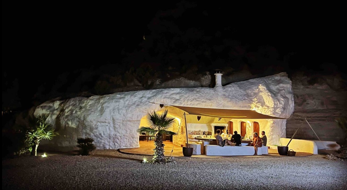 White cave home with a lounge area in front