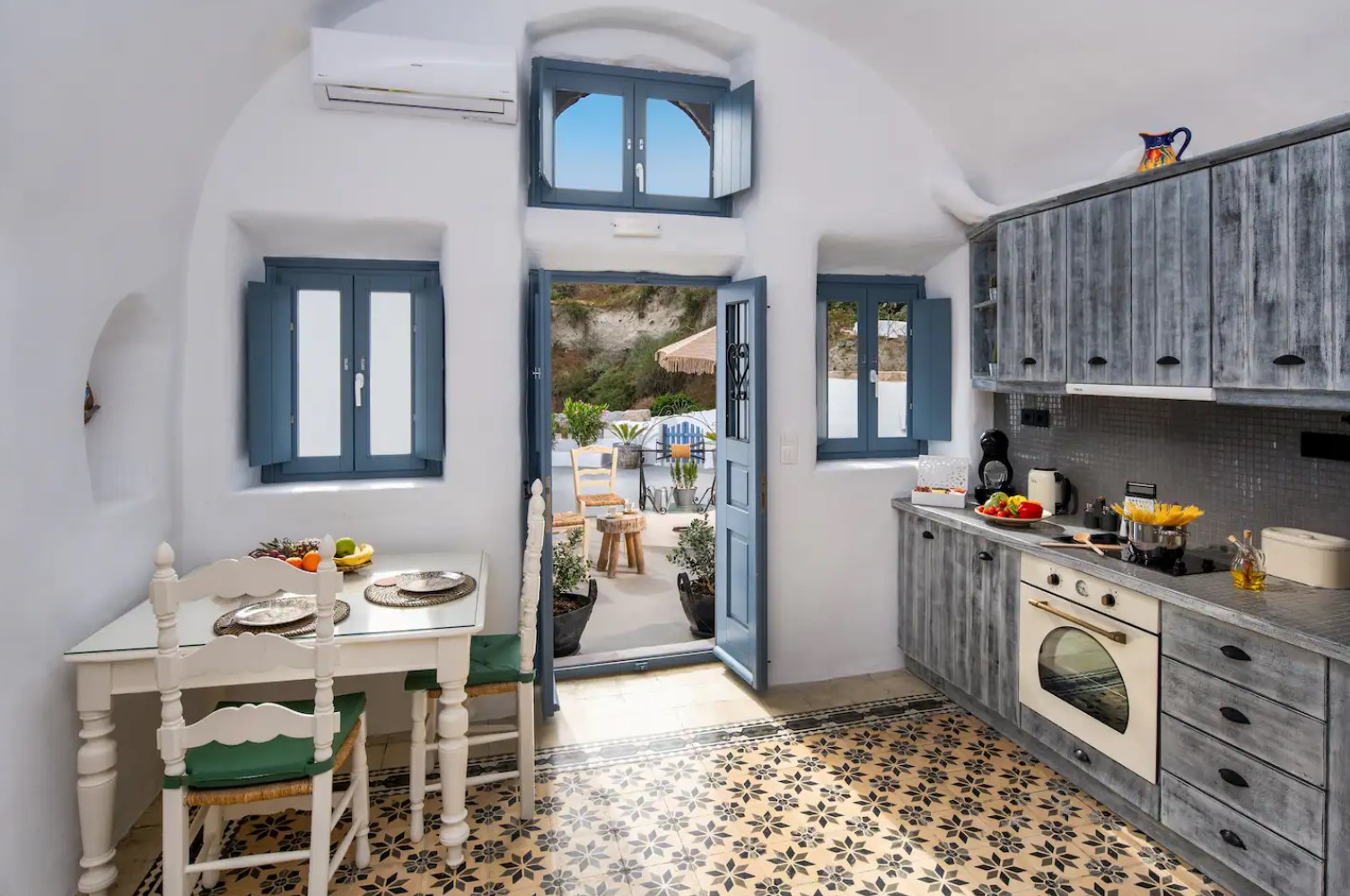 White kitchen of a cave home with blue windows and doors