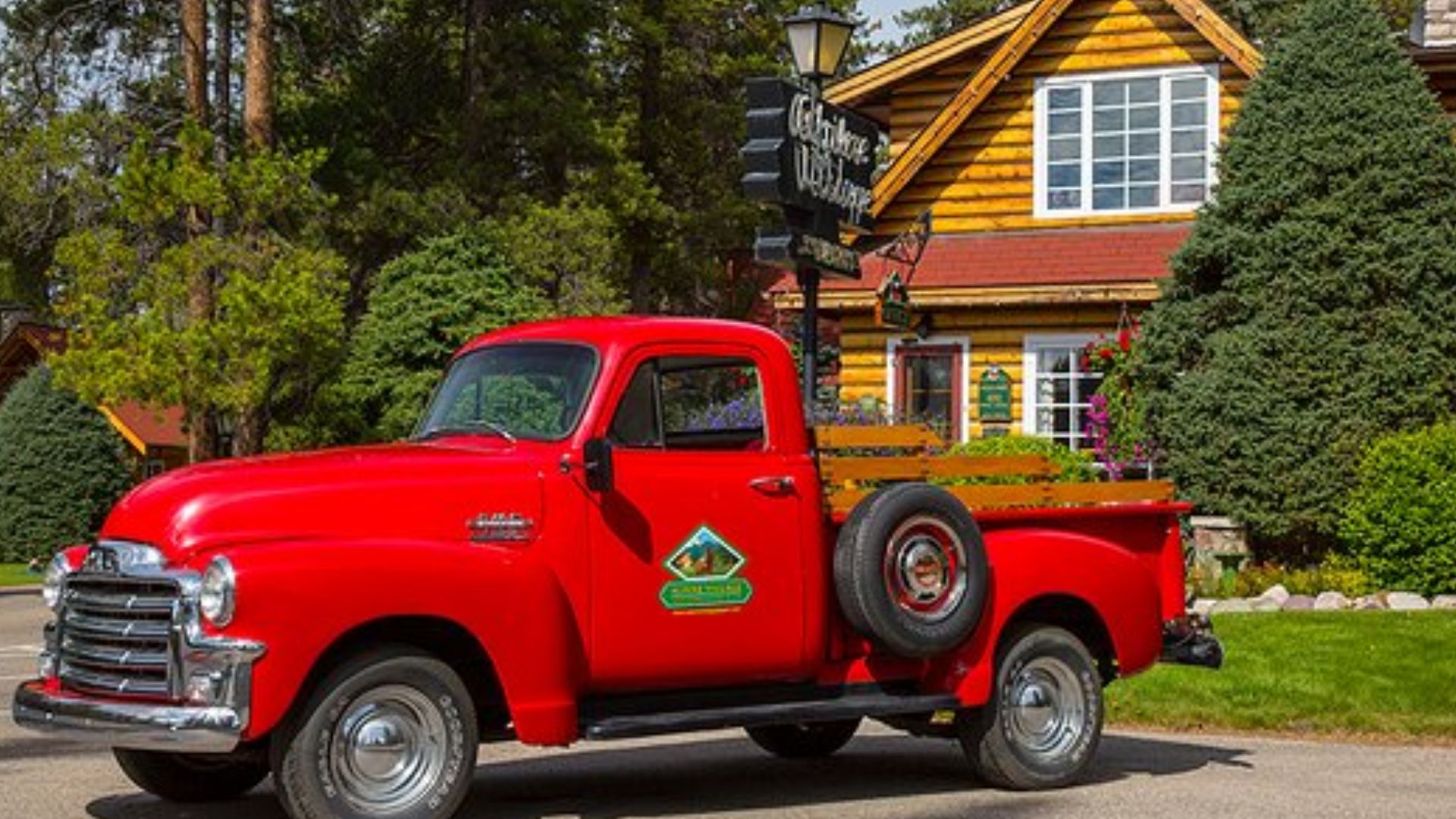 red pickup truck with a log cabin behind