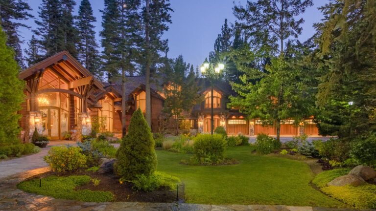 exterior of a big cabin with floor to ceiling windows surrounded by the woods
