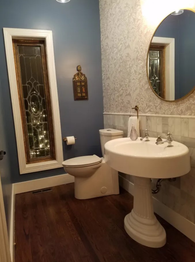 bathroom with a blue wall, white tiled wall, flower patterned wall, white sink and white toilet after renovation