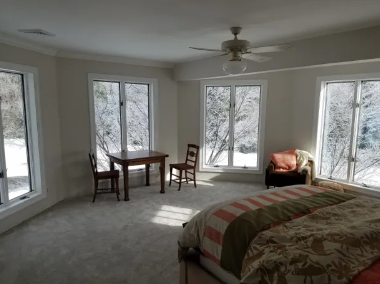 bedroom with big windows, bed, wooden tables and chairs, and a sofa after renovation