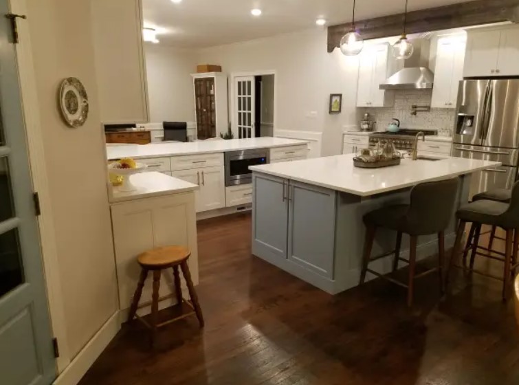 kitchen with a white island accompanied by chairs and white cabinets and white countertop after renovating