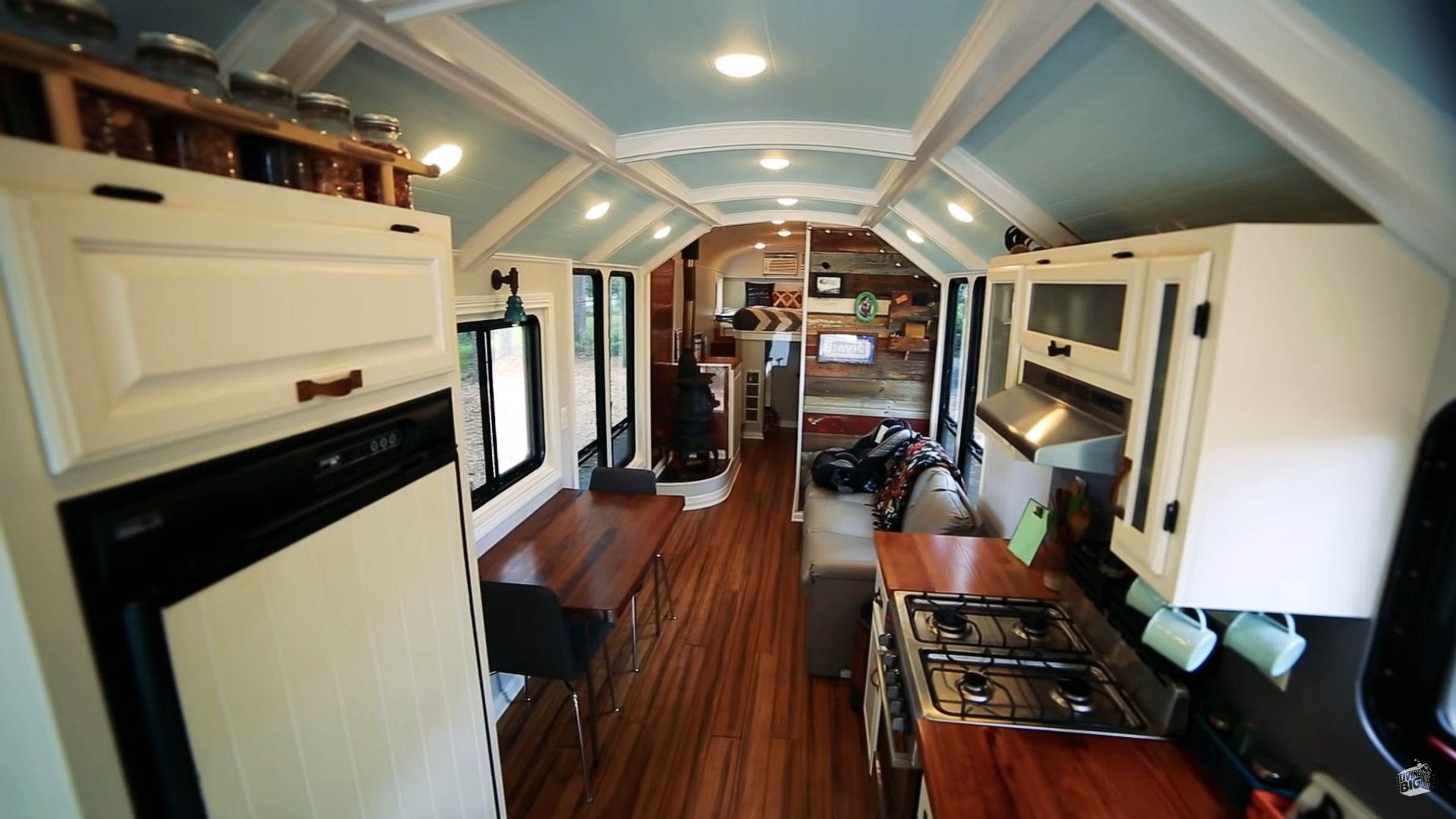 interior of a converted school bus home with wooden countertops, wooden table and black chairs