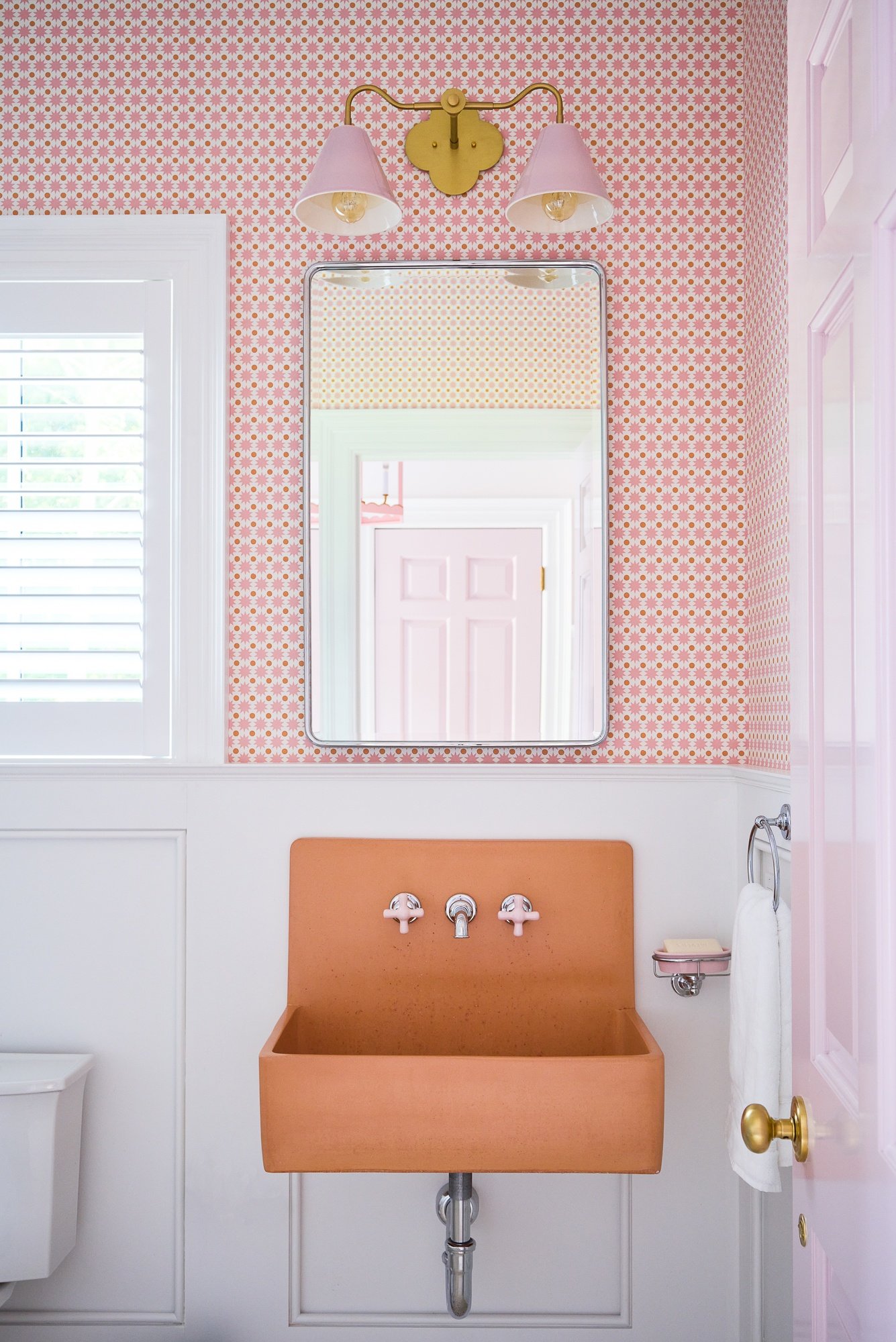 bathroom with a pink wallpaper and an orange sink and a rectangular mirror above it