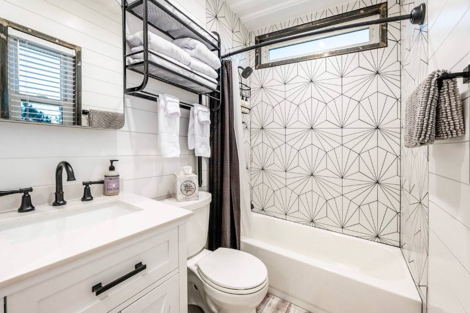 bathroom with patterned tiles, white bathtub, white cabinet and white sink