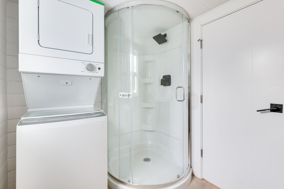 bathroom with a round, glass shower, stacked washer and dryer