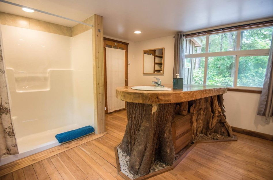 bathroom with a wooden countertop and lower part and a white sink, big shower and a big window