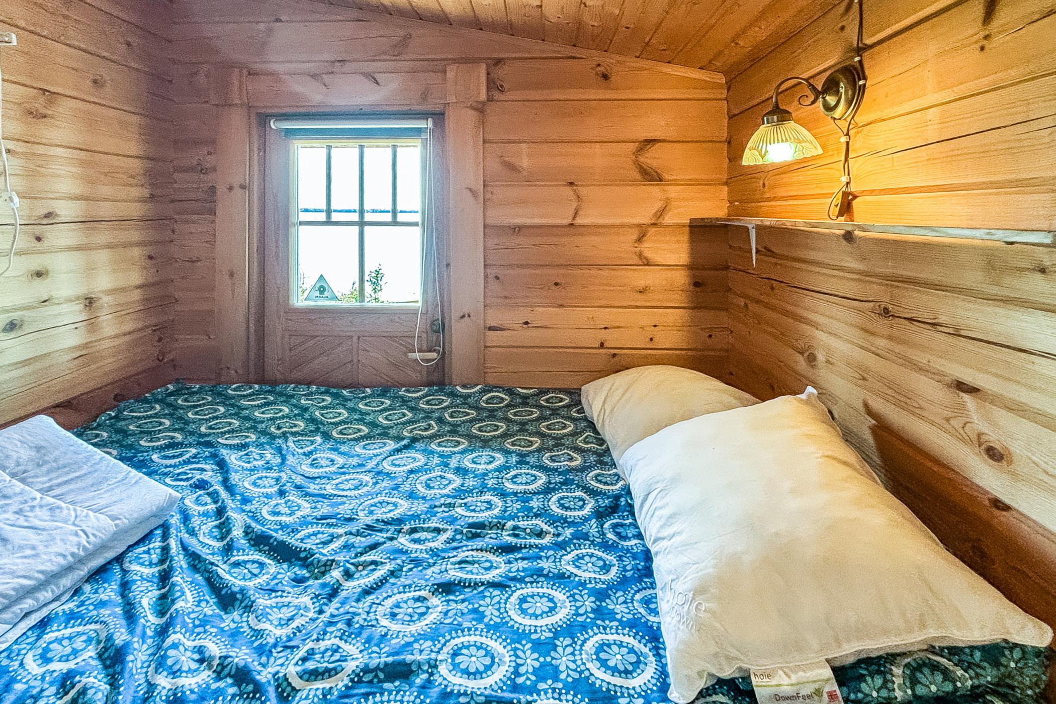 bedroom with a big bed, tiny window and a lamp above the bed