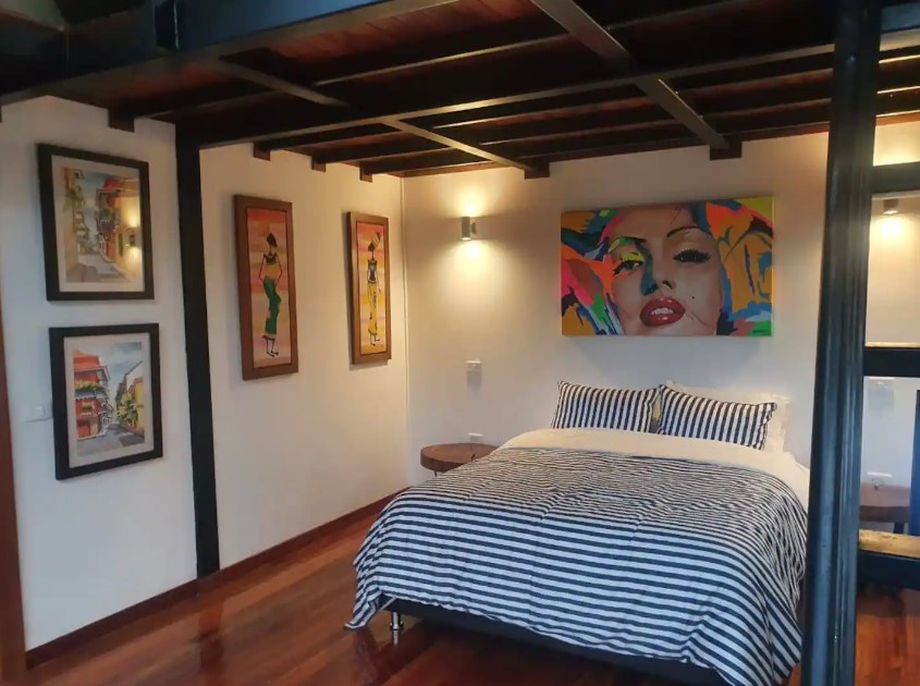 bedroom with artworks on the walls, round brown bedside tables around the bed