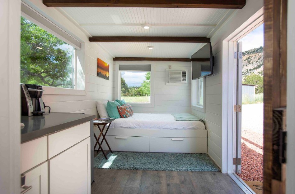 bedroom with a big bed, windows around the bed, flat screen tv