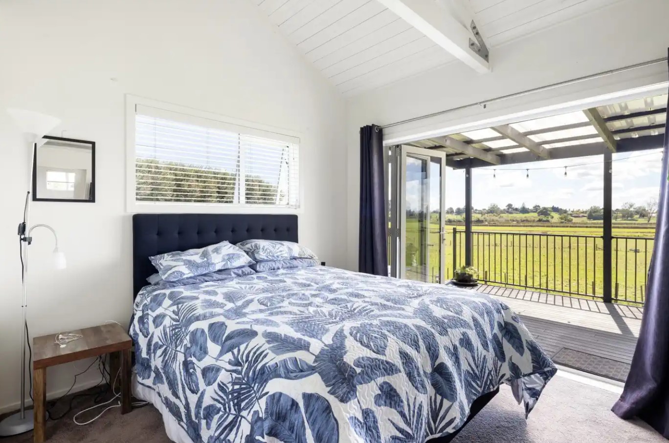 bedroom with glass doors and the view on the side of the bed, white walls and a bed