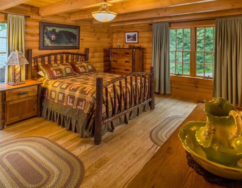 bedroom with wooden walls, wooden bed frame, wooden cabinets and two windows