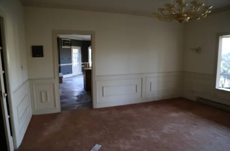 empty dining room with white walls and old flooring before renovation