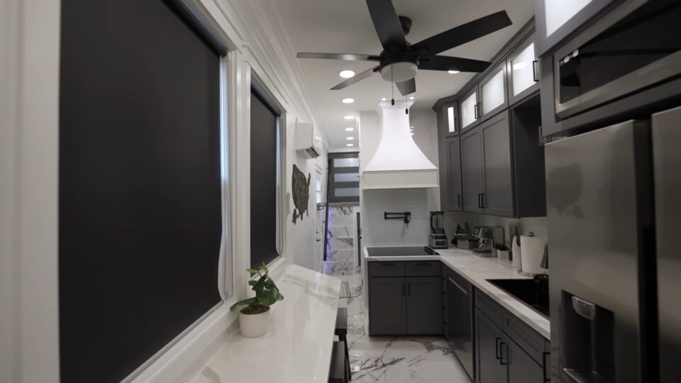 interior of a converted school bus home with black cabinets and white countertops