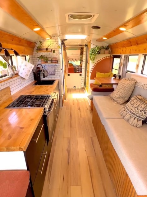 interior of a converted school bus home, wooden countertop, wooden shelves