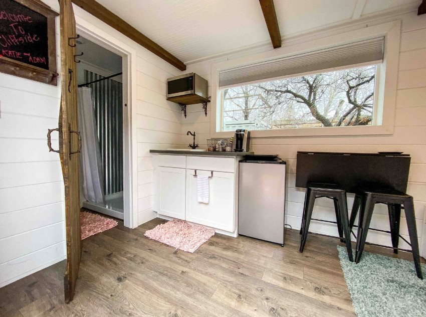 brown farmhouse doors on the loft and white cabinets and a foldable black table with black stools on the right