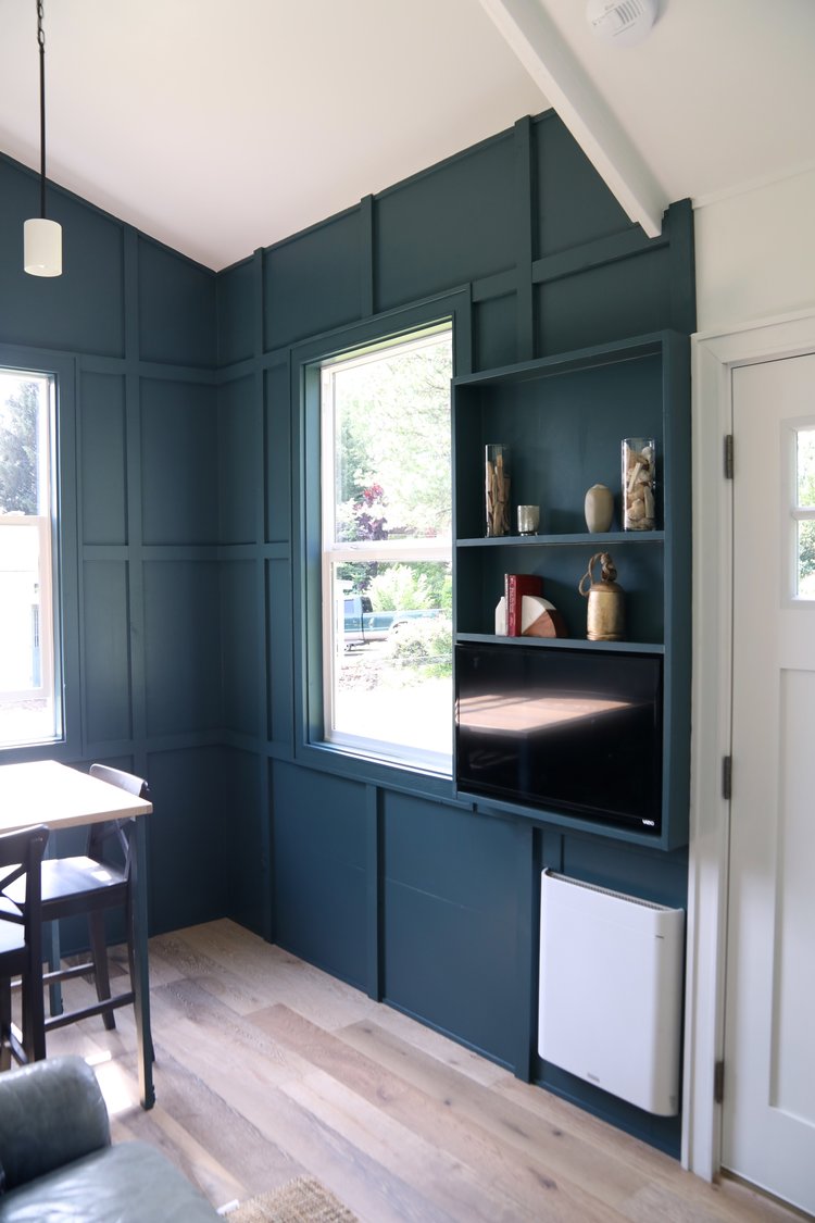 room with dark teal walls, built in shelves with decor and a flat screen tv