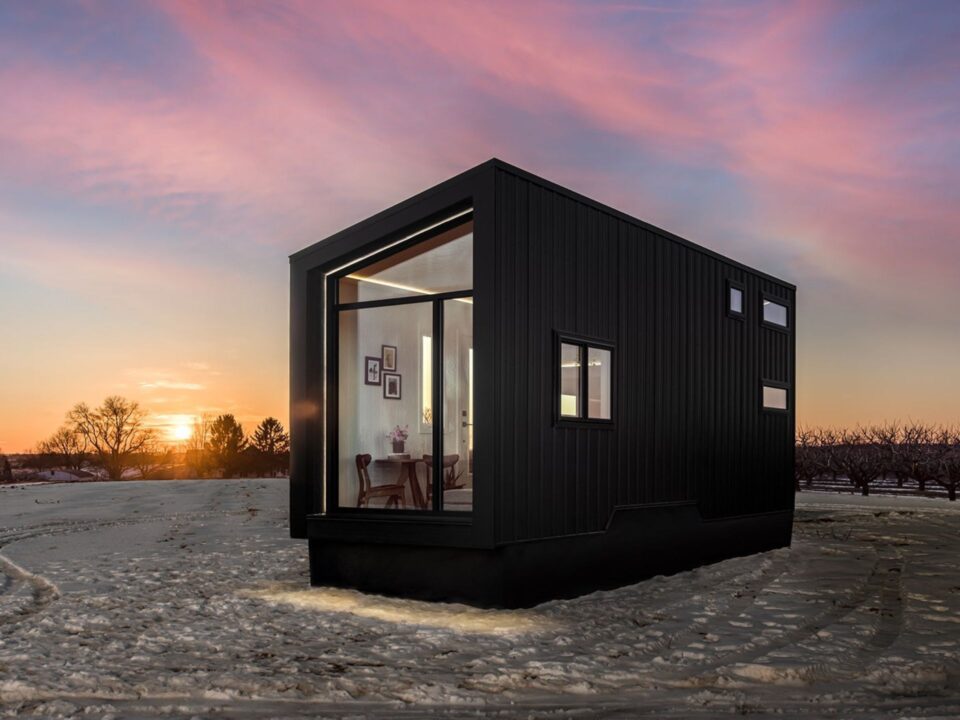 exterior of a tiny home with black walls and white interior walls during a sunset