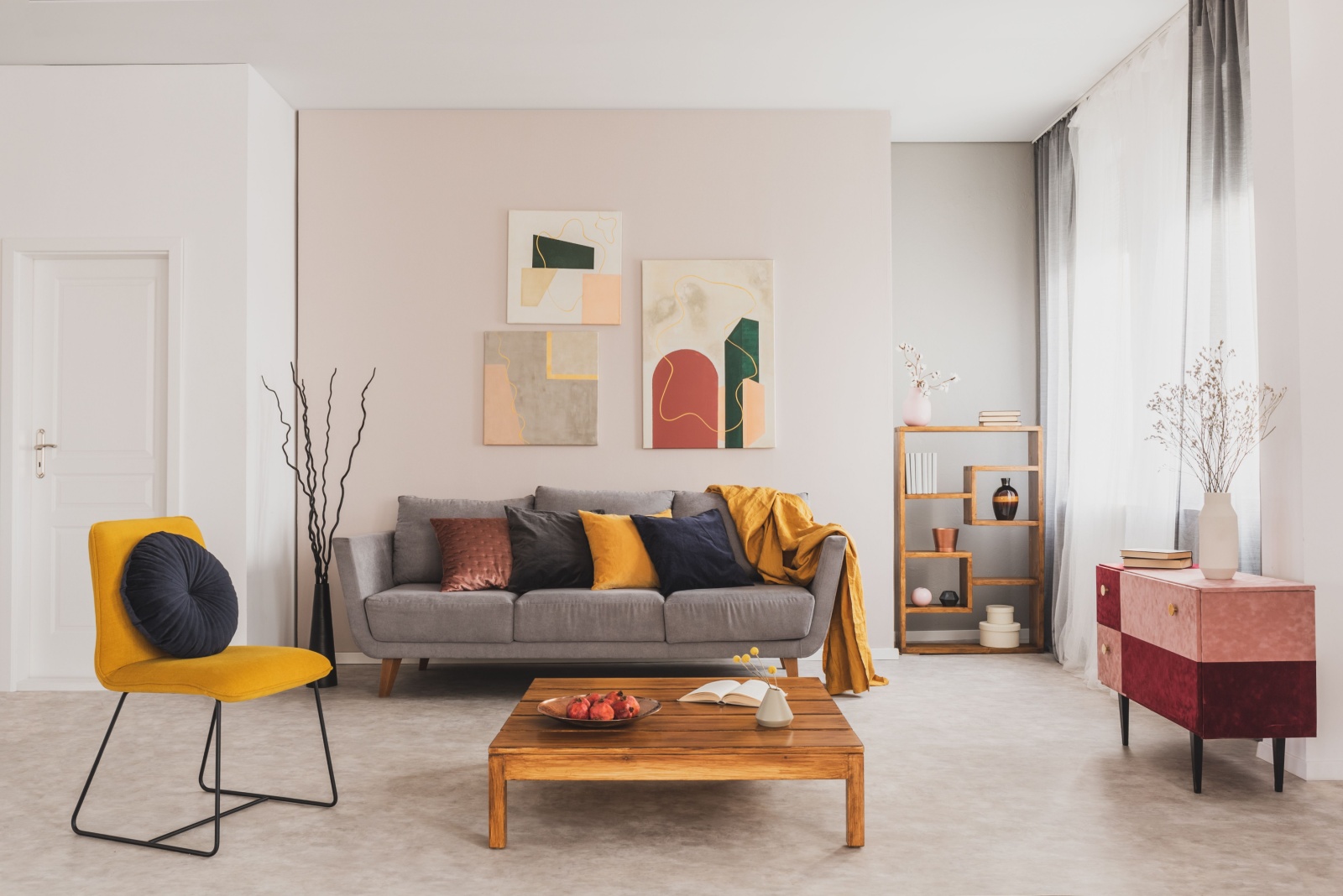 living room with a gray couch, wooden table, wooden shelf, colorful pillows