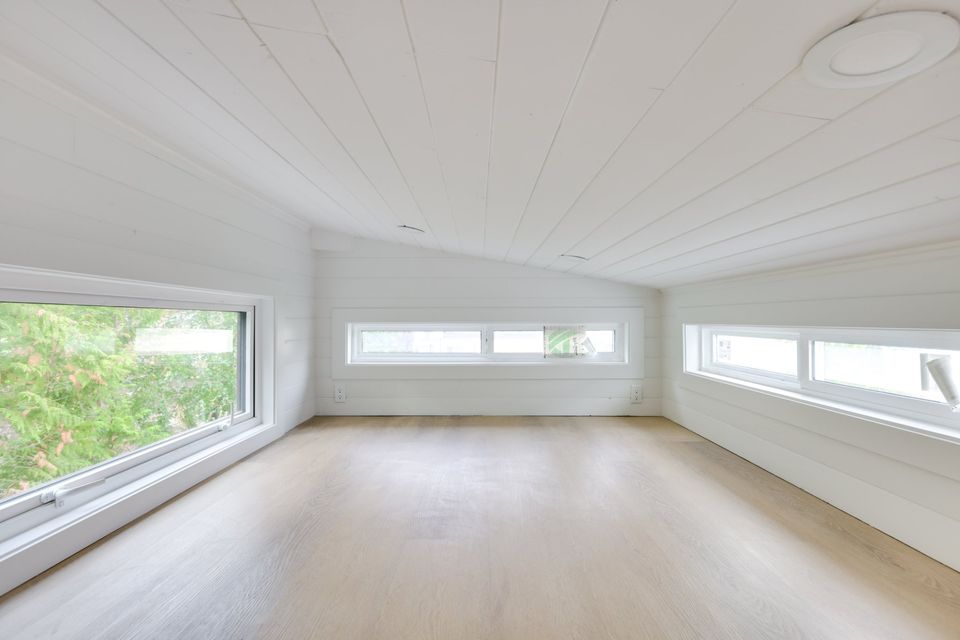 empty loft bedroom with white walls and three windows