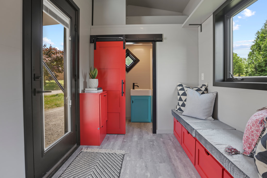 entry and living room with a built in couch with red drawers, red doors, red cabinet, blue cabinet in the bathroom, glass doors and a big window