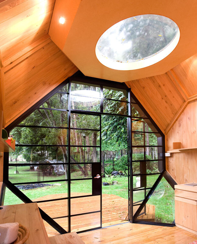 interior of a polyhedron tiny home with glass doors, ceiling window and wooden walls