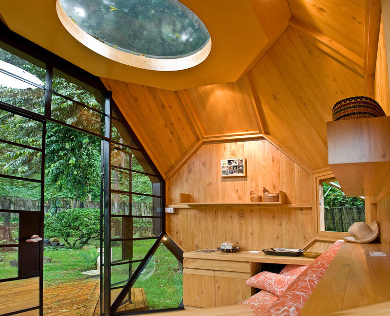 interior of a polyhedron tiny house with wooden walls, wooden shelves, wooden cabinets, textured orange couch