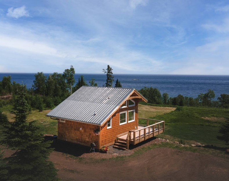 exterior of a cabin surrounded by the trees and the lake